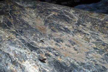 Texture of granite on a boulder stone. Close-up on the surface of a granite stone. The stone has different colors of white-brown and gray shades. The plane of the stone is not even.