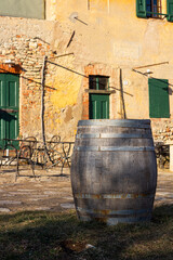 Traditional wooden wine barrel, typical rustic italian stone house in the background. Copy space