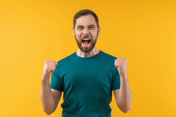 Attractive euphoric bearded man clenching his fist in triumph celebrating money win at bookmaker's website - 426489549