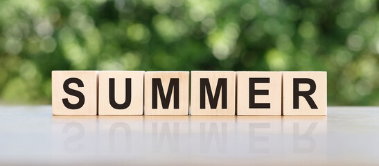 Summer word written in wooden cube on wooden table