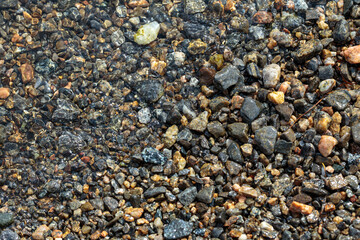Small stones and pebbles in the surf on the beach