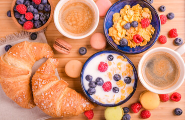 Espresso coffee with froth, croissants, Muesli with berries and milk. Delicious healthy breakfast. Flakes and sweet pastries. High quality photo