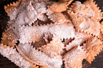 Italian Carnival and TYPICAL food. Sfrappole or chiachiere or angel wings and aromatic coffee on a woody background.Traditional sweet crisp pastry deep-fried and sprinkled with powdered sugar. Above