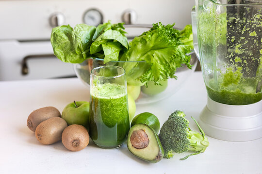 yummy ripe green fruits and vegetables on the kitchen table with a glass and blender to make a healthy and delicious green smoothie from fresh fruits and vegetables, vegan and vegetarian drink for