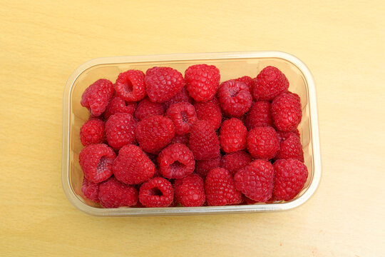 Fresh sweet raspberries in clear plastic box