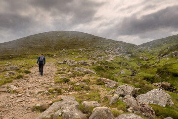 Foot path to the top of Croagh Patrick and one tourist. Low clouds over mountains peak, travel and...