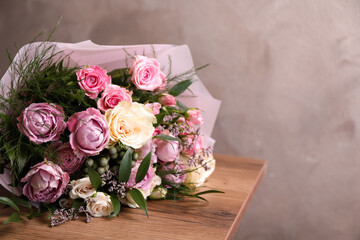Beautiful bouquet with roses on wooden table. Space for text