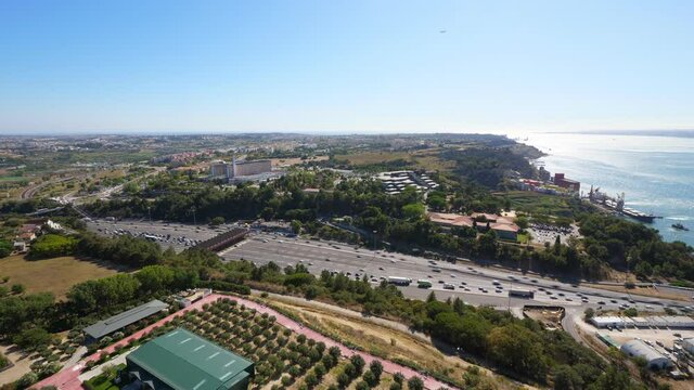 Wide highway area at toll gates, time lapse shot from above. Lively car traffic on lanes, vehicles ride at Almada side, from and to 25 de Abril bridge. Green landscape and Tagus river seen on back
