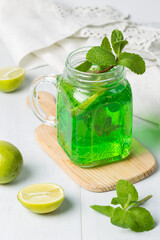 Bright emerald lemonade with tarragon extract, mint and lime. A natural refreshing cocktail.In a glass mug, close-up, vertical