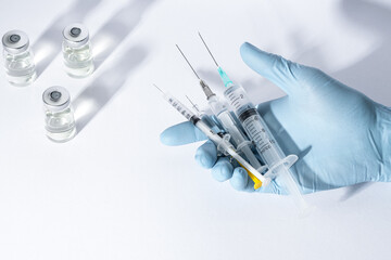 Doctor's hands in blue gloves hold different syringes with medicine, vaccine, antibiotics.