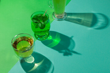 The concept of natural carbonated drinks. Kombucha, elderflower lemonade and tarragon. In a glass on a green and blue paper background, hard shadows. Horizontally with space