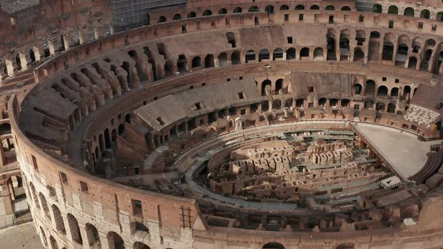 Aerial view of Colosseo or Colosseum, travel landmark in Rome, Italy. Flavian Amphitheatre or Coliseum in Roma seen from drone flying in sky. Tourist attraction with scaffolding for restoration