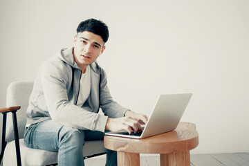 The programmer is sitting on the couch at home in front of the computer. Wireless headphones in the ears. A male freelance designer of European appearance works on a laptop. Online training.