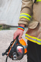 Fototapeta na wymiar firefighter holding helmet, with LGBT bracelet. Vertical photo