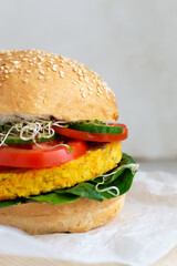 Veggie burger with chickpea, merrove, onion and garlic cutlet with tomato, cucumber, spinach and microgreen. Vegetarian food concept. Vertical orientation. Close-up.