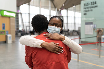 African American couple wear medical face masks hugging, embrace each other within the new...