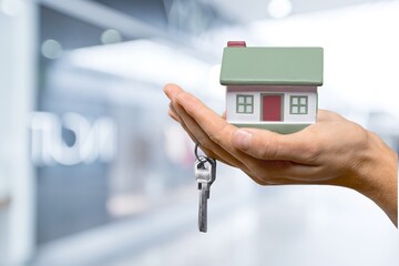 Human hand holding house model and keys