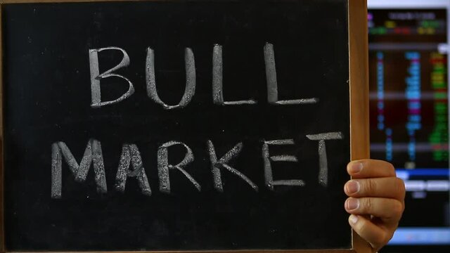 Trader  with bull market  word , blurred stock exchange board background.