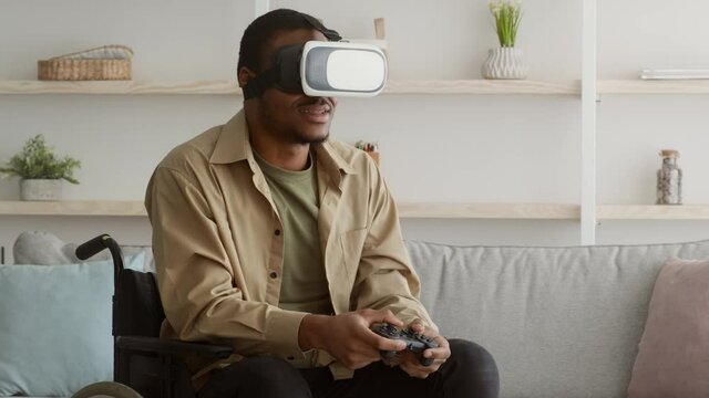 Disabled Guy In Wheelchair Wearing VR Glasses Playing Videogame Indoor