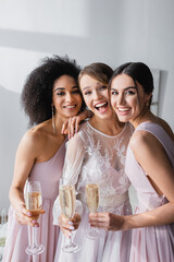 excited bride with friends smiling at camera while holding champagne glasses.