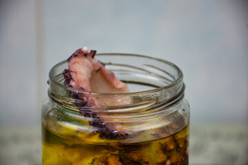 close up view of a marinated octopus with olive olio in the jar