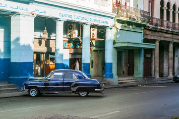 Fototapeta premium Cuban Arab Cultural Center with a vintage mid-century navy blue car parked in front of it, Havana, Cuba