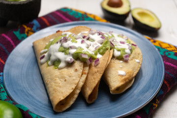 Fried tacos with guacamole and sour cream on white background. Mexican food