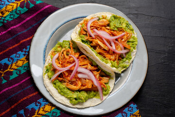 Chicken tinga tacos with guacamole and onion on dark background. Mexican food