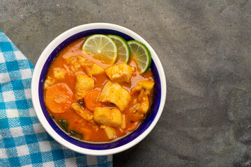 Fish soup with vegetables on grey background. Mexican food