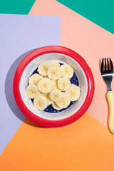 Cutted banana in bowl on colorful background