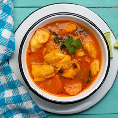 Fish soup with vegetables on turquoise  background. Mexican food