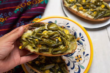 Molletes with poblano rajas and cheese on white background. Mexican food