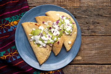 Fried tacos with guacamole and sour cream on wooden background. Mexican food
