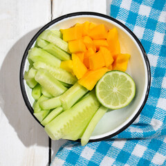 Cucumber and mango salad on white background