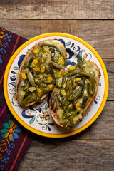 Molletes with poblano rajas and cheese on wooden background. Mexican food