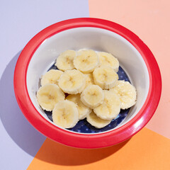 Cutted banana in bowl on colorful background