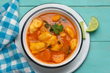 Fish soup with vegetables on turquoise  background. Mexican food