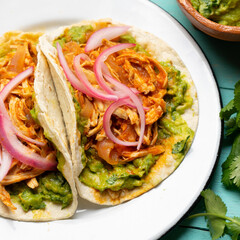 Chicken tinga tacos with guacamole and onion on turquoise background. Mexican food