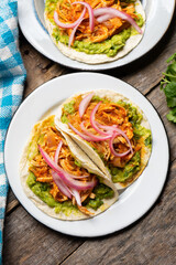 Chicken tinga tacos with guacamole and onion on wooden background. Mexican food