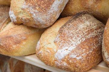 Large loafs of traditional white flour bread. Fried crust of bread. Wooden shelf. Bakery concept.