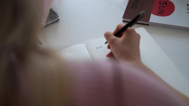 A woman in love writes into her diary words -dear diary-. Writing down memories.