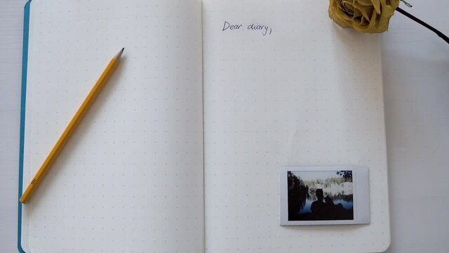 An open girl´s diary with a words -dear diary- with a pen, photo and rose. Love and dream.