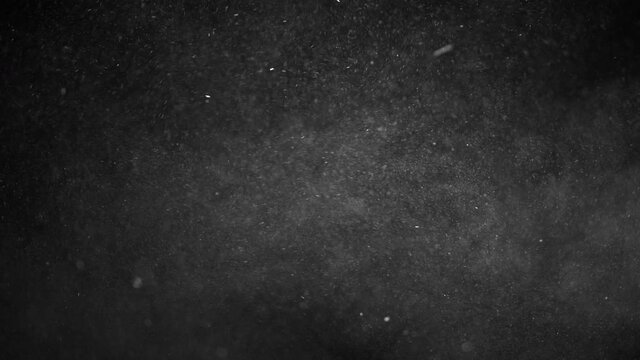 Small macro Dust particles floating in the air and falling on black background close-up