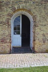 Fototapeta na wymiar Colonial Arched Wooden Door on Brick Building in Daylight