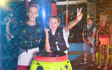 Portrait of excited teen boy and girl with laser guns during lasertag game in dark room..