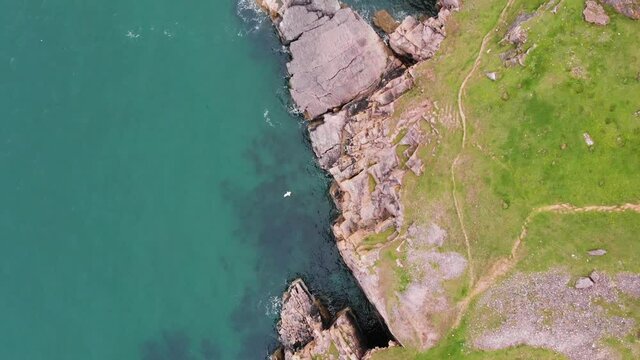 Smooth Revealing Drone Shot of Worms Head, Rhossili Bay and Rhossili Beach in The Gower Peninsula, Wales. Showing Crashing Waves Hitting off The Rocks