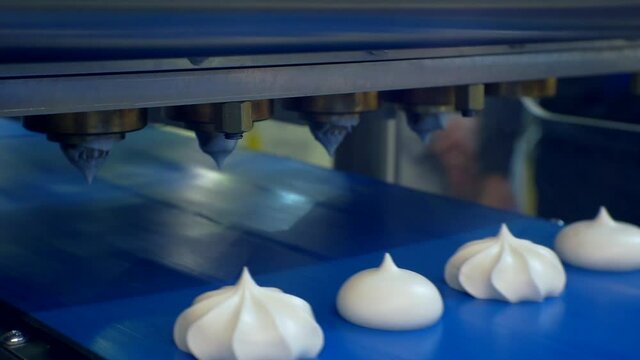 modern food production. a special machine makes cakes from thick cream. the finished cakes move slowly along the conveyor belt. filming a close-up of a technological process. shallow depth of field.