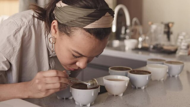 Lockdown of professional female barista tasting different types of coffee in cup tasters in restaurant. Coffee degustation