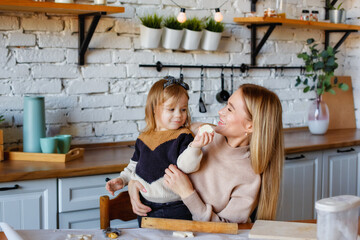 Funny little baby helper playing with dough on his hands learning to knead helps adult mom in the...
