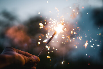 Bright sparkler in a male hand in the blurred background